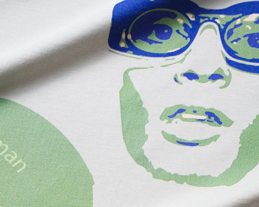 Close-up of a dtg graphic on fabric, featuring a stylized face with glasses in green and blue tones, with partial text visible.