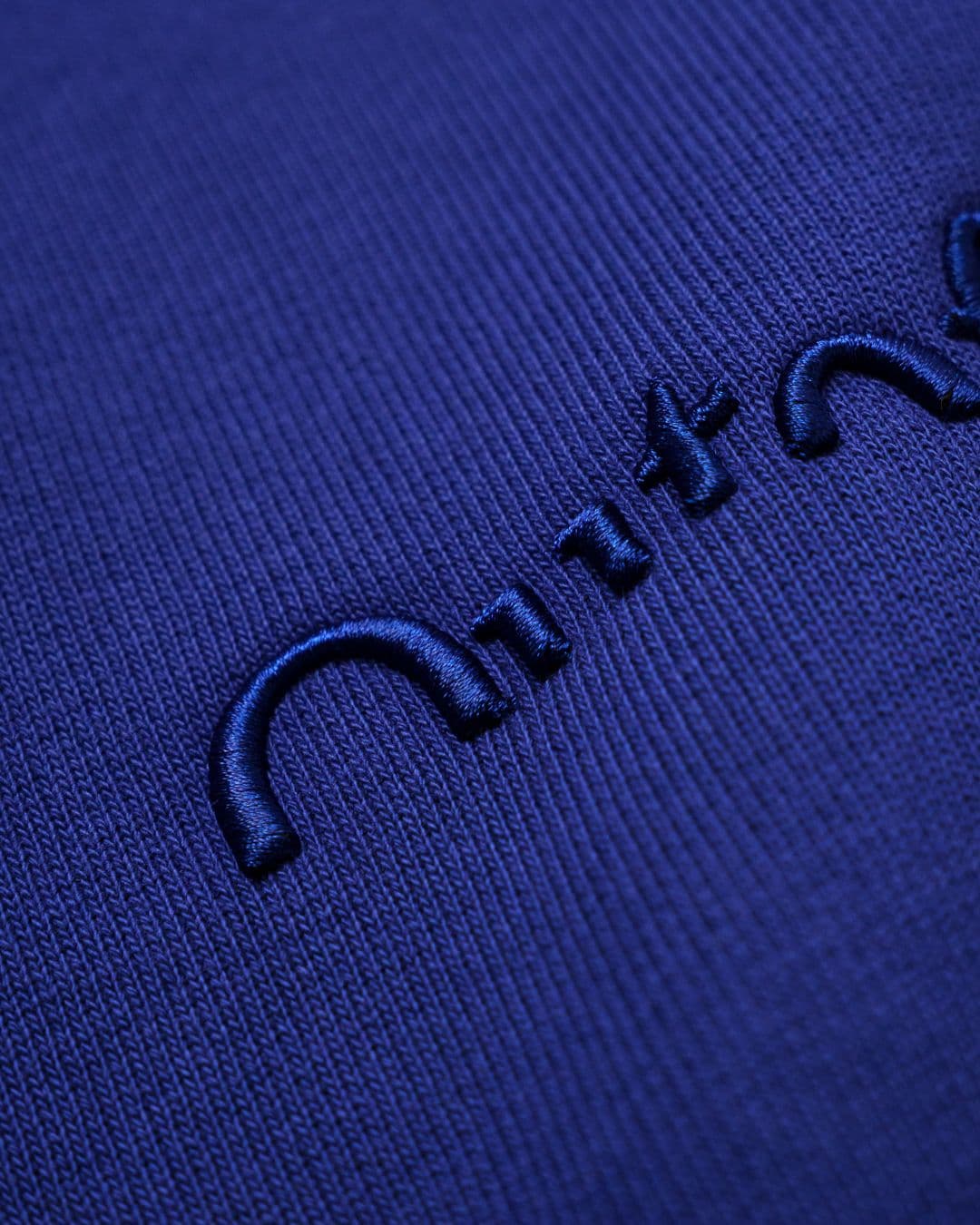 Close-up of 3D embroidery on blue fabric, showing raised stitching that adds depth and texture to the design.