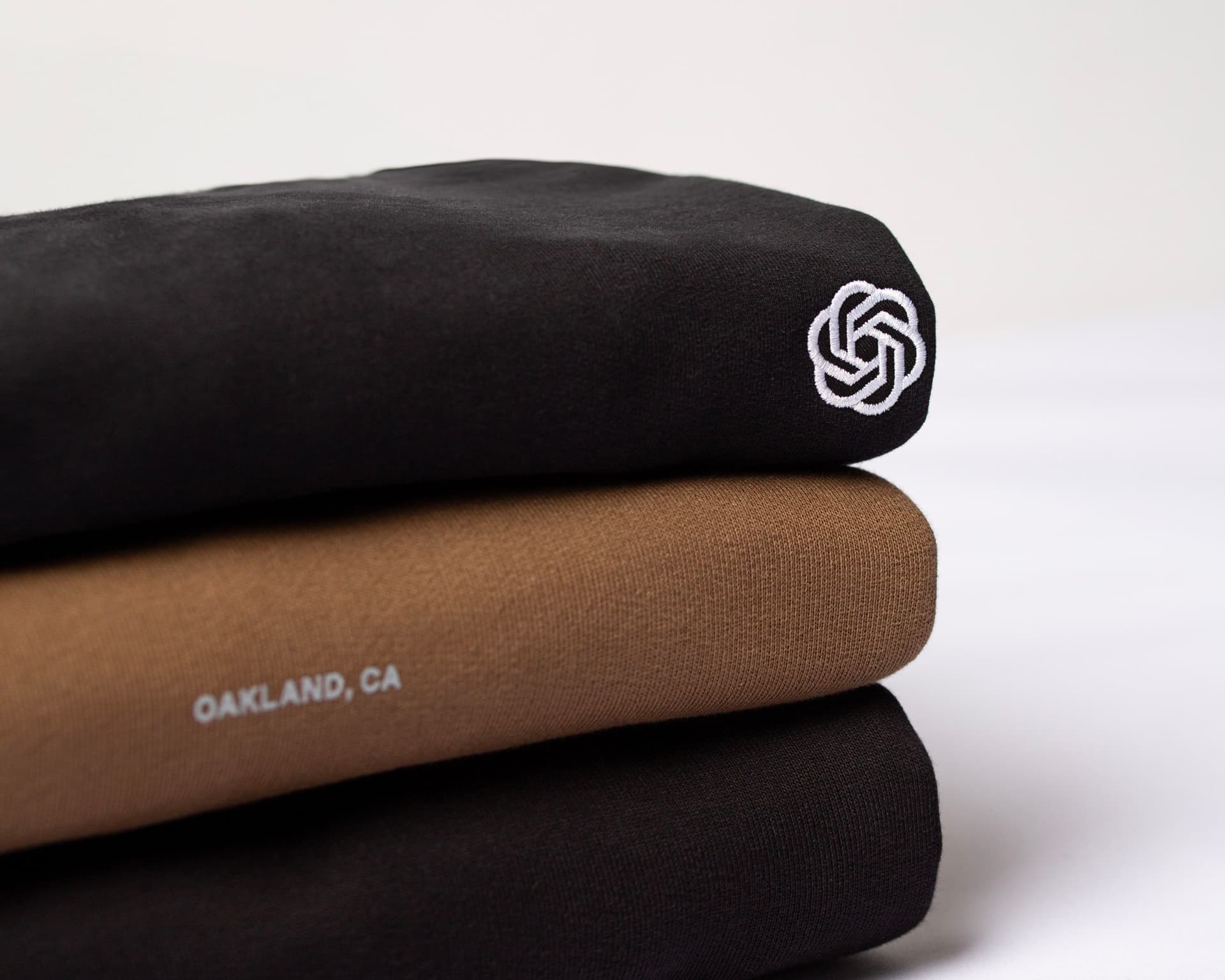 Stack of embroidered sweatshirts showing logo detail and stitched text.