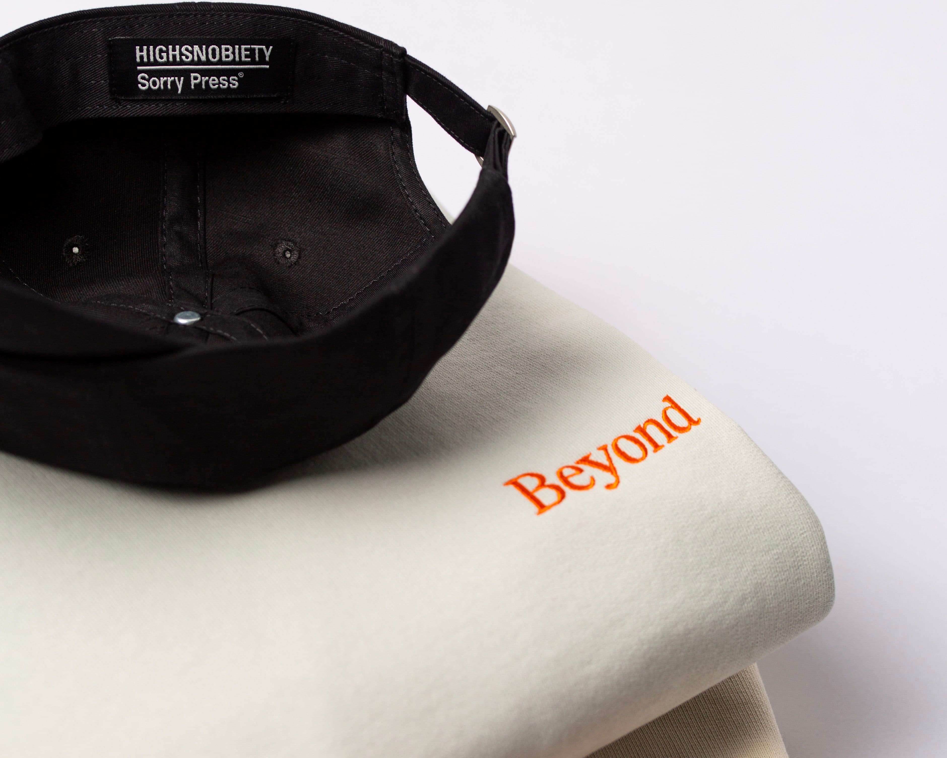 Black cap and folded apparel made by Assembly for brands including Highsnobiety and Beyond.