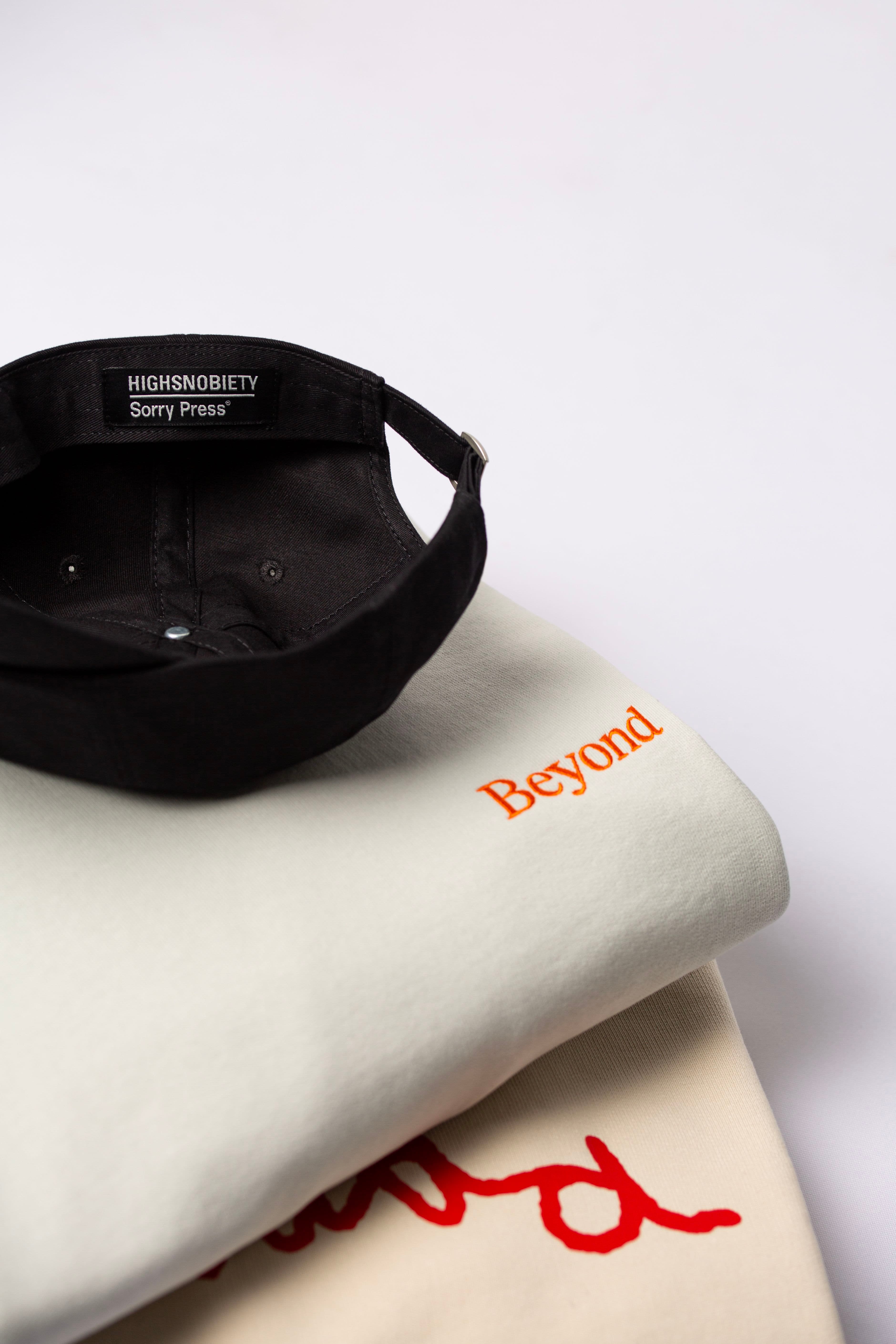 Stack of embroidered branded sweatshirts and a custom cap on top