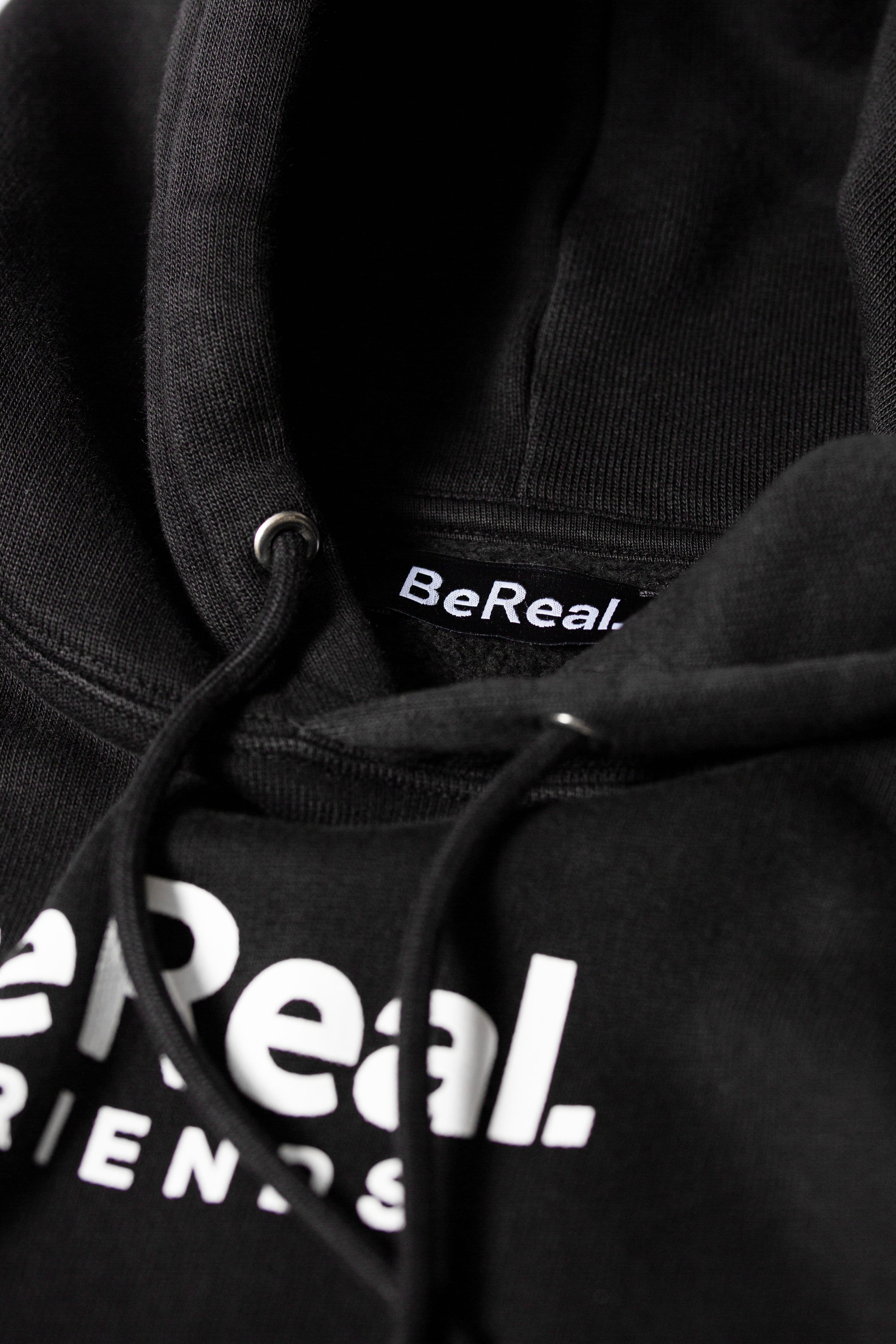 Close-up of a black custom hoodie showing premium print "BeReal" and woven neck label.