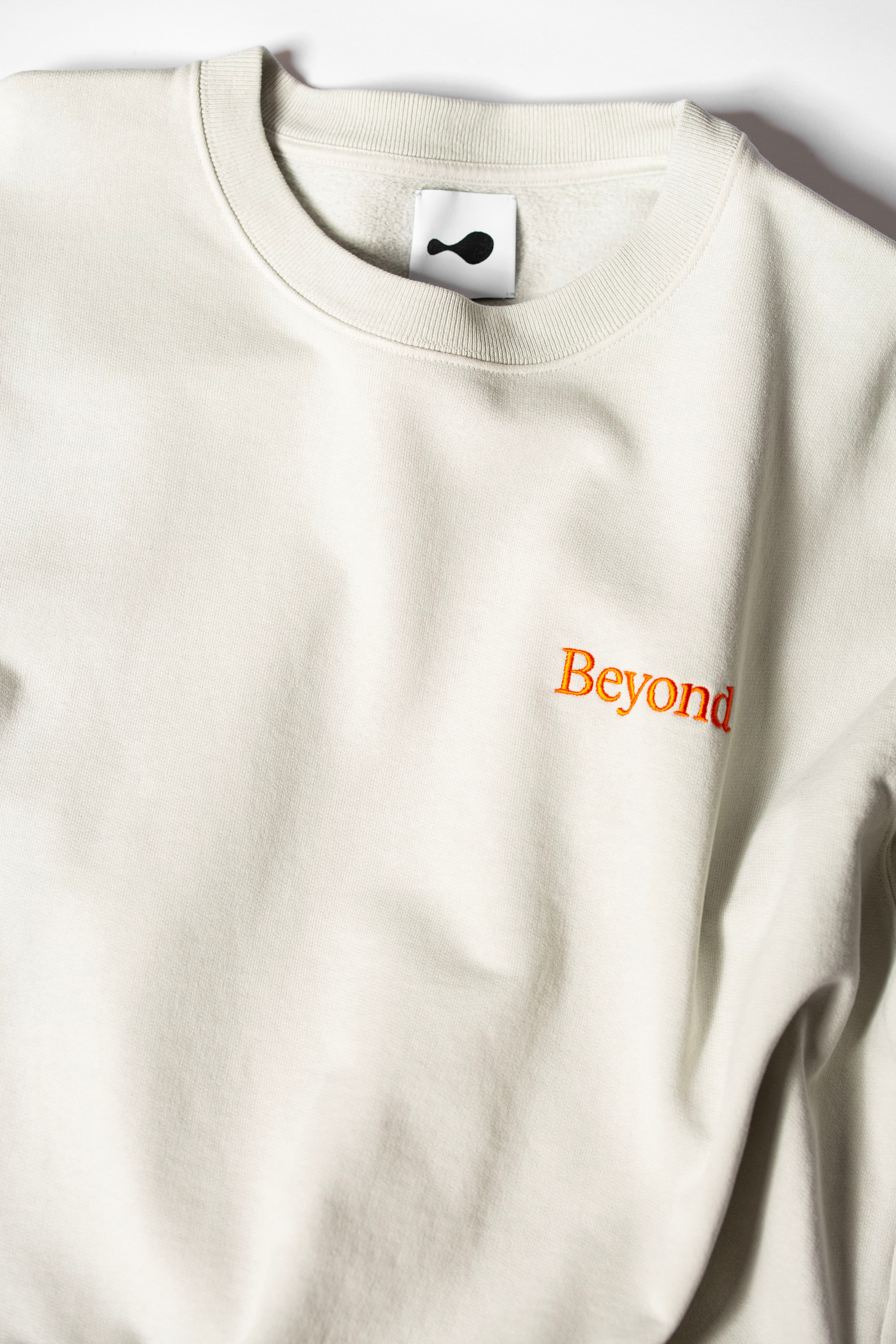 Cream sweatshirt with Beyond logo embroidered in orange thread.