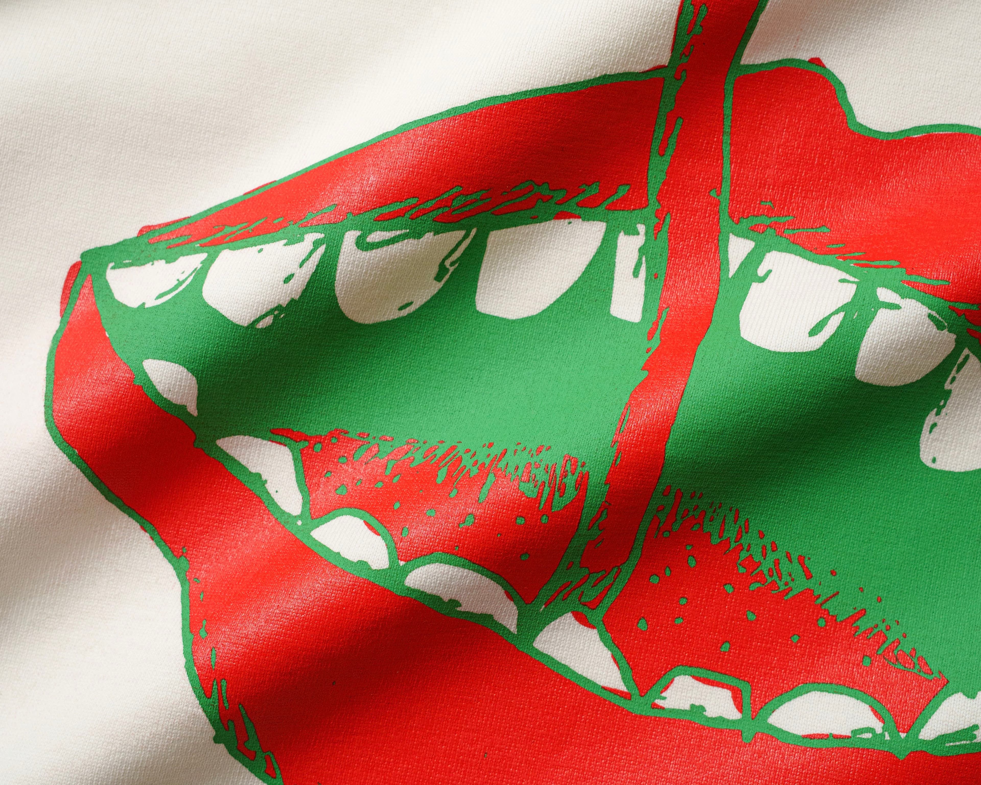 Close-up of a red and green mouth graphic screen print on white cotton fabric.