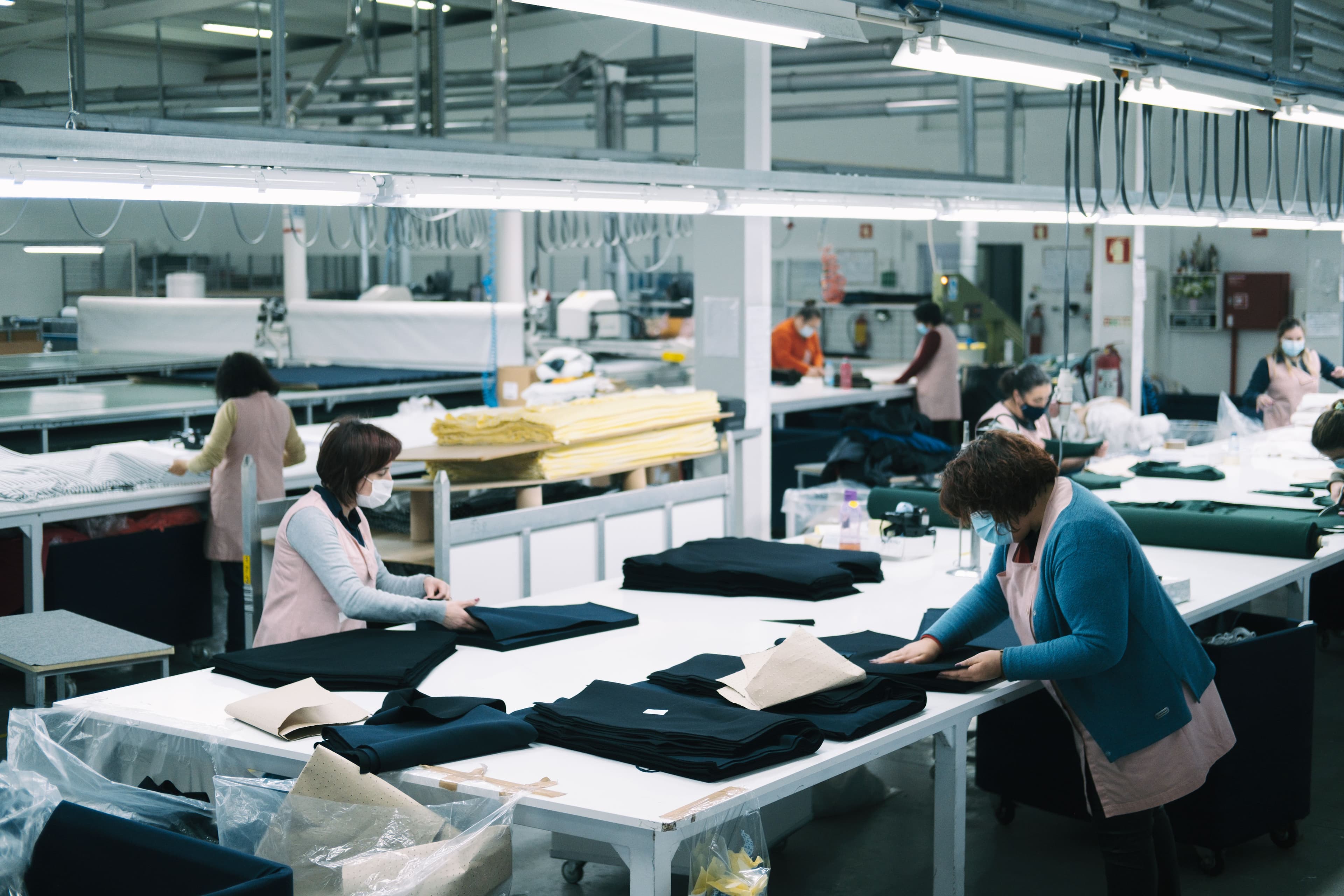 Workers folding and sorting garments in a clean production facility.