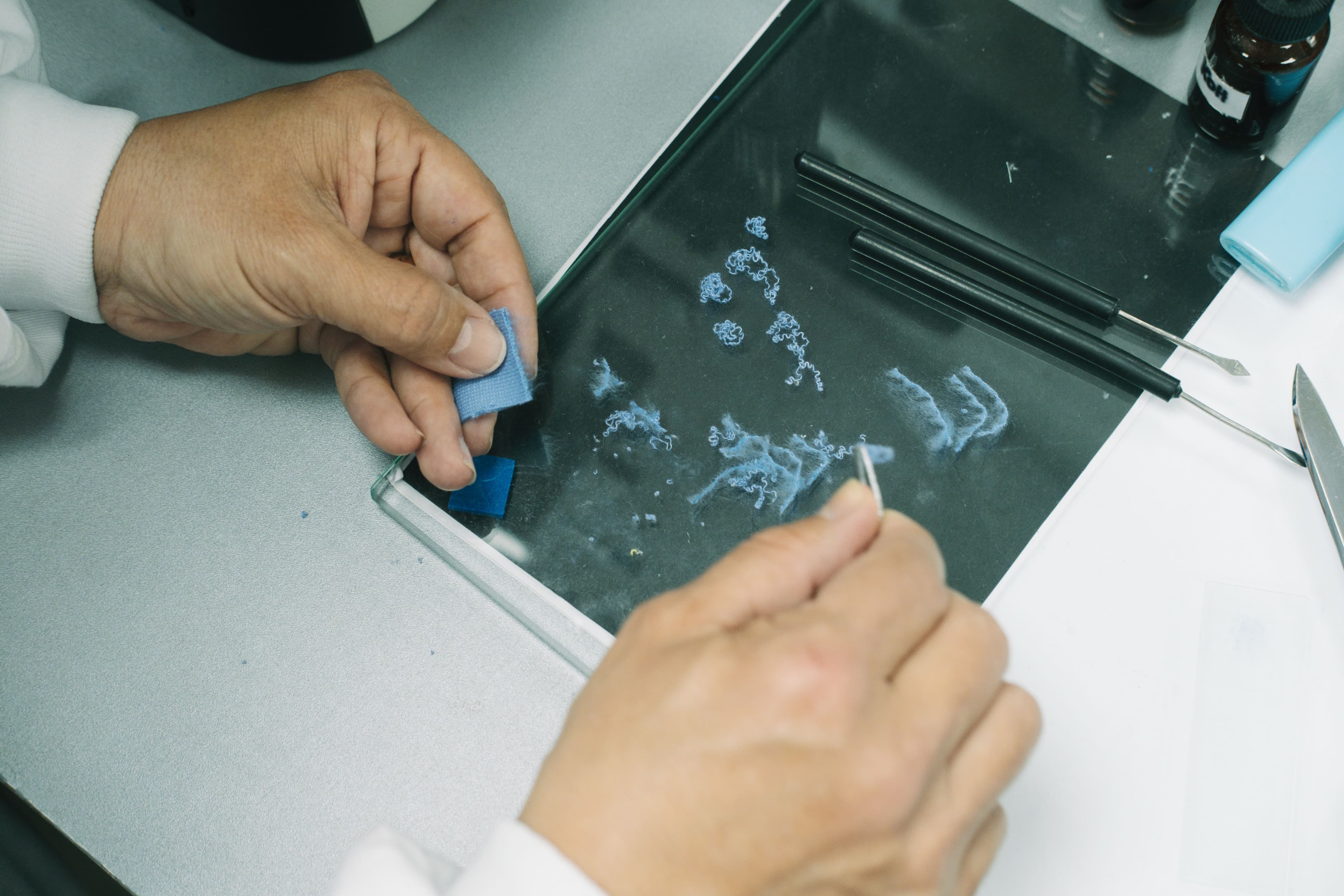 Close-up of fabric swatches being inspected during garment dyeing quality control at Assembly.