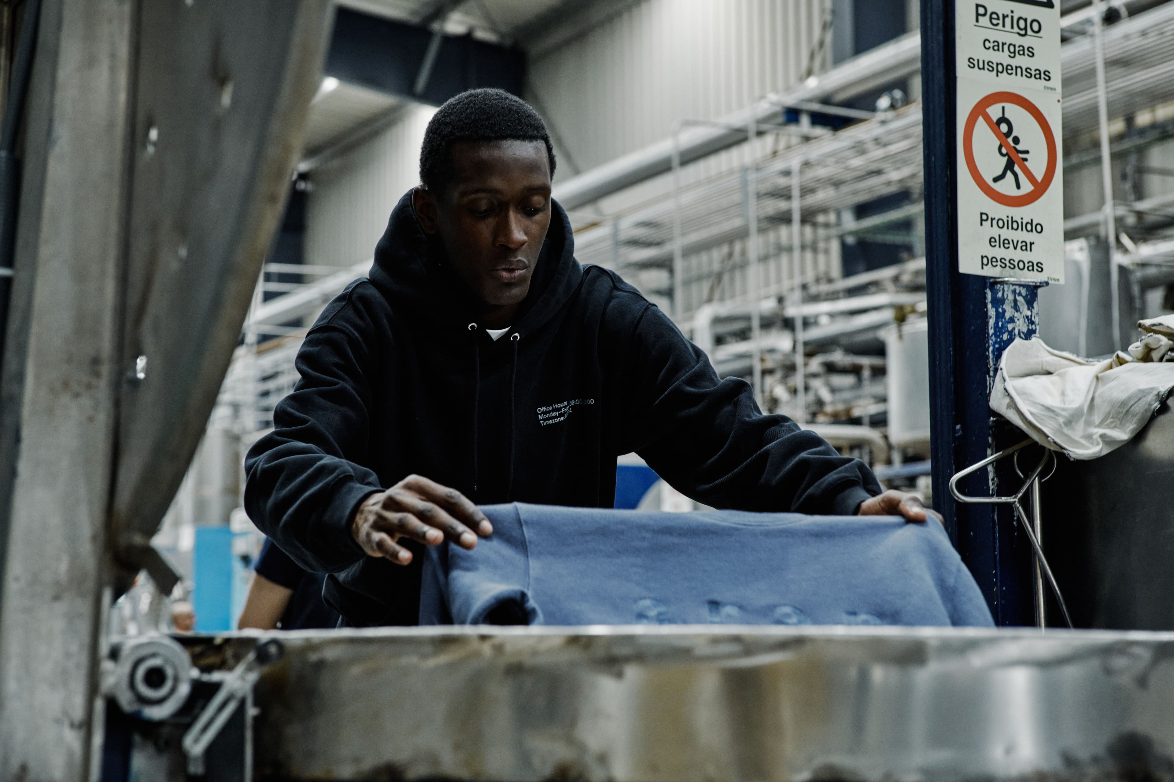 Worker handling sweatshirt during dyeing process in factory.